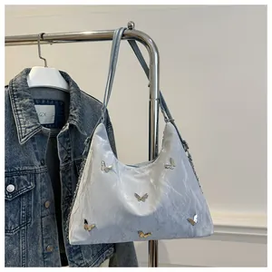Detail view of light blue tote with metallic butterflies and wrinkled leather texture