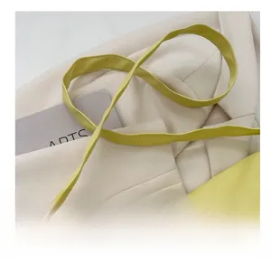 Detail view of the stitching and slender shoulder strap on a light yellow leather bag