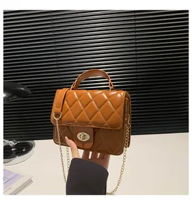 Detail of a brown quilted leather crossbody bag with golden chain and oval turn-lock closure