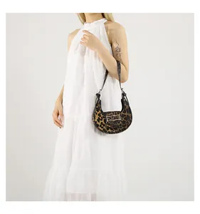 Close-up of leopard print crescent shoulder bag with metallic buckle detail on white dress