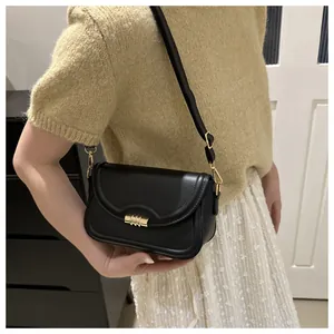 Close-up of a black leather crossbody square bag with a signature gold metal lock buckle