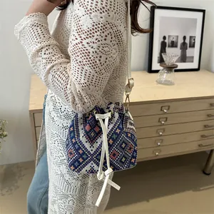 Close-up of ethnic style woven bucket bag with leather drawstring and gold hardware details