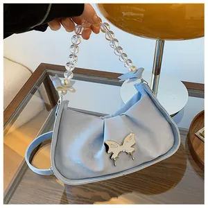 Détail d'un sac à main plissé bleu clair avec boucle papillon et anse en perles