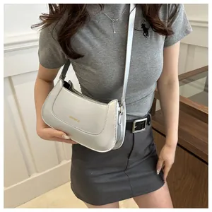 Silver metallic crossbody bag with minimalist stitching worn by model in a casual setting
