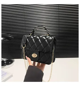 Detail of black quilted leather crossbody bag with gold metal lock and chain strap