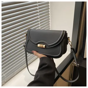 Detailed shot of a black patent leather crossbody bag with a gold textured twist lock