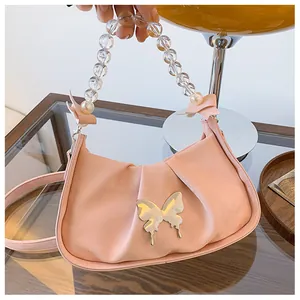 Détail du sac plissé rose avec boucle papillon miroir et poignée en perles élégante