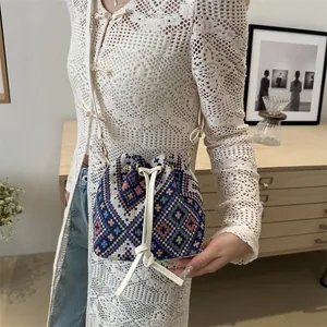 Close-up of geometric ethnic pattern weaving on a bucket bag with leather drawstring detail