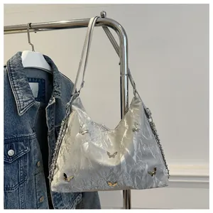 Macro detail of metallic silver pleated texture with butterfly charms on tote bag