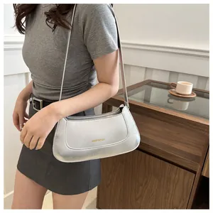 Detail showing the silver gray faux leather texture and gold logo on this crescent bag