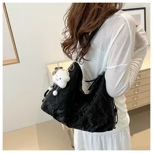 Detail of black pleated hobo bag texture with branded logo and cloud plush charm