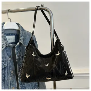 Detail view of black hobo bag with silver butterfly buckles and leather chain strap
