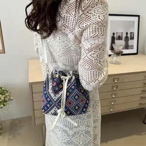 Detailed view of bohemian embroidered bucket bag with colorful geometric patterns and drawstring