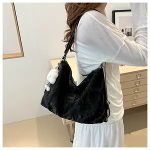 Detail of black tote bag featuring crinkled texture fabric and a white plush toy charm