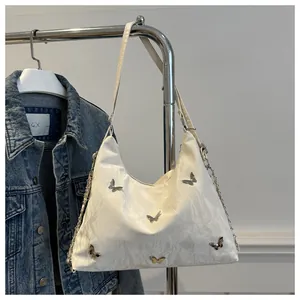 Detail of white pleated tote bag with silver butterfly charms and dual chain straps