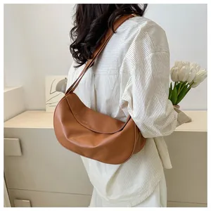 Detailed texture of brown crescent shoulder bag in PU leather on casual striped shirt