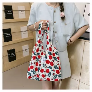 Vue détaillée du motif floral de roses rouges et logo cousu sur le sac en toile