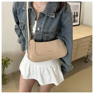 Close-up of cream faux leather crossbody bag with golden branding and adjustable strap