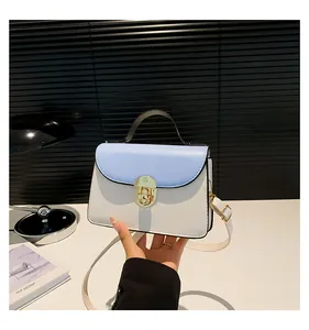 Dettaglio della borsa a tracolla blu e bianca con chiusura girevole dorata e texture pelle