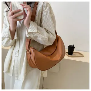 Close-up of caramel brown crescent shoulder bag showing matte faux leather texture and curves