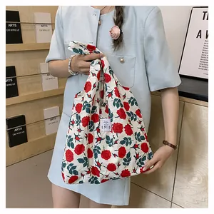 Gros plan sur le sac cabas en toile à fleurs avec roses rouges et étiquette de marque EMIS