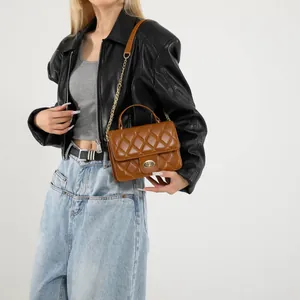 Brown quilted crossbody bag with gold chain strap worn by a model in a leather jacket