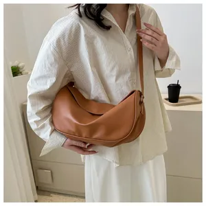 French chic crescent moon leather crossbody bag worn by a model in a minimal setting