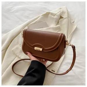 Close-up of brown matte leather crossbody bag featuring a golden twist-lock and arch stitching