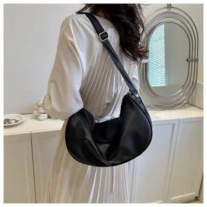 Detail of black textured leather hobo bag featuring adjustable strap and golden buckle