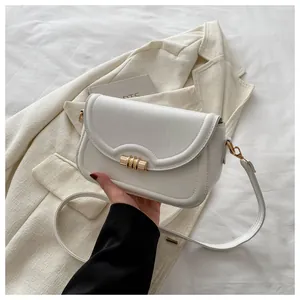 Detail of white PU leather crossbody bag with golden cylindrical metal twist lock