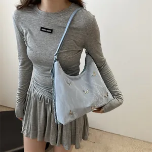 Light blue nylon tote bag with metallic butterfly accents and silver chain detail