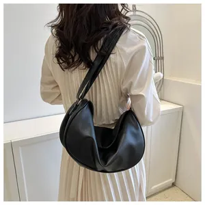 Close-up of black crescent moon bag with lychee leather texture on model shoulder