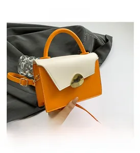 Detail of vibrant orange and cream crossbody bag with irregular gold metal buckle closure