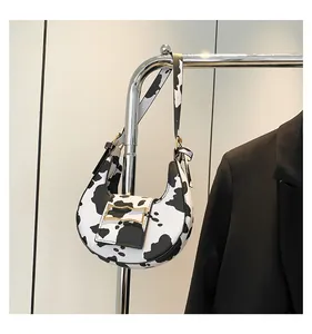 Detail view of the sleek cow print underarm bag with elegant gold metal buckle and strap