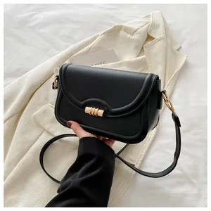 Detailed close-up of compact black leather crossbody bag with cylindrical gold metal lock