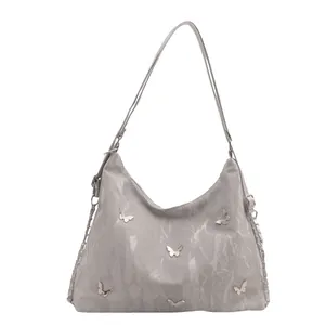 Chic grey tote bag with butterfly metal accents and chain strap on white background
