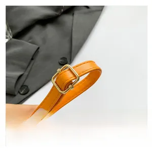 Detail of adjustable bright orange synthetic leather shoulder strap with gold metal buckle