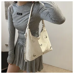 Detail of off-white shoulder bag with silver butterfly studs and metallic chain strap