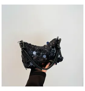 Close-up of black sequined crescent bag with metallic shine and knotted strap detail