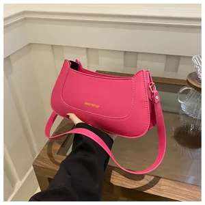Detail of rose pink matte leather crossbody bag with golden lettering and precise stitching