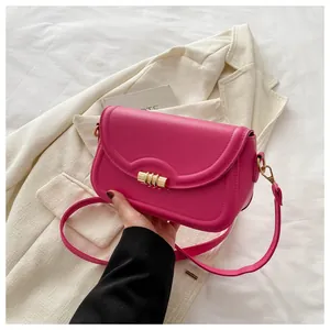 Close-up of magenta leather handbag featuring wave-edge flap and golden metal twist lock