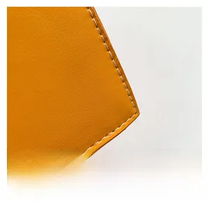 Macro shot of yellow leather texture with white contrast stitching detail on shoulder bag