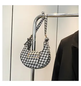 Detail of a houndstooth pattern underarm bag with gold metal buckle and black blazer