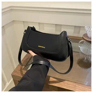 Detail of black crescent shoulder bag with gold JINGPINPIJU lettering and PU leather texture