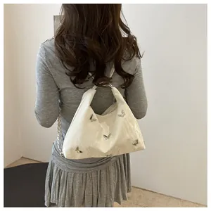 Close-up of white glossy patent leather bag featuring silver metal butterfly decorations