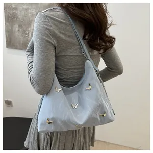 Hobo bag detail featuring silver butterfly ornaments and light blue nylon material