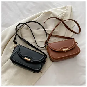 Flat lay of minimalist black and brown crossbody bags with gold cylindrical metal clasps