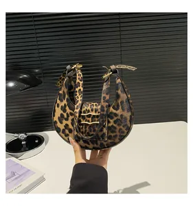 Close-up of leopard print crescent bag with adjustable wide strap and gold metal buckle