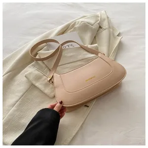 Detail view of the beige matte leather handbag with gold lettering and slim shoulder strap