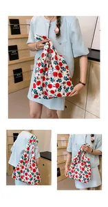 Détail du sac cabas en toile à fleurs roses avec écusson logo EMIS sur tissu blanc